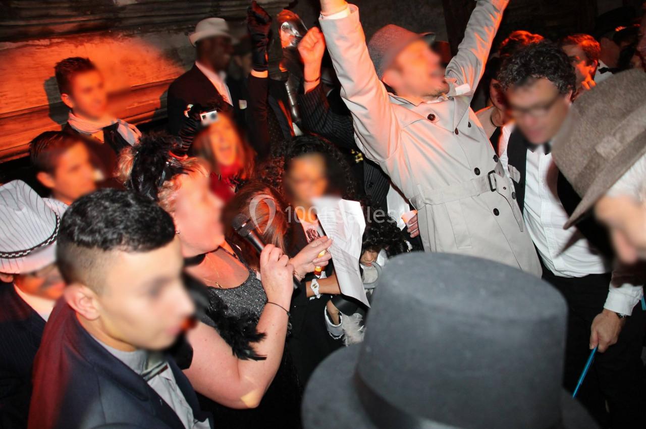 Personnes en tenue de soirée dansant et célébrant dans un lieu animé avec une ambiance festive.