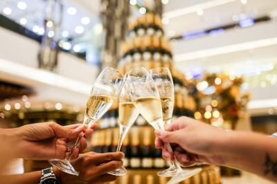 Ours en peluche avec un nœud rose devant un présentoir de cupcakes décorés dans un décor rose et lumineux.