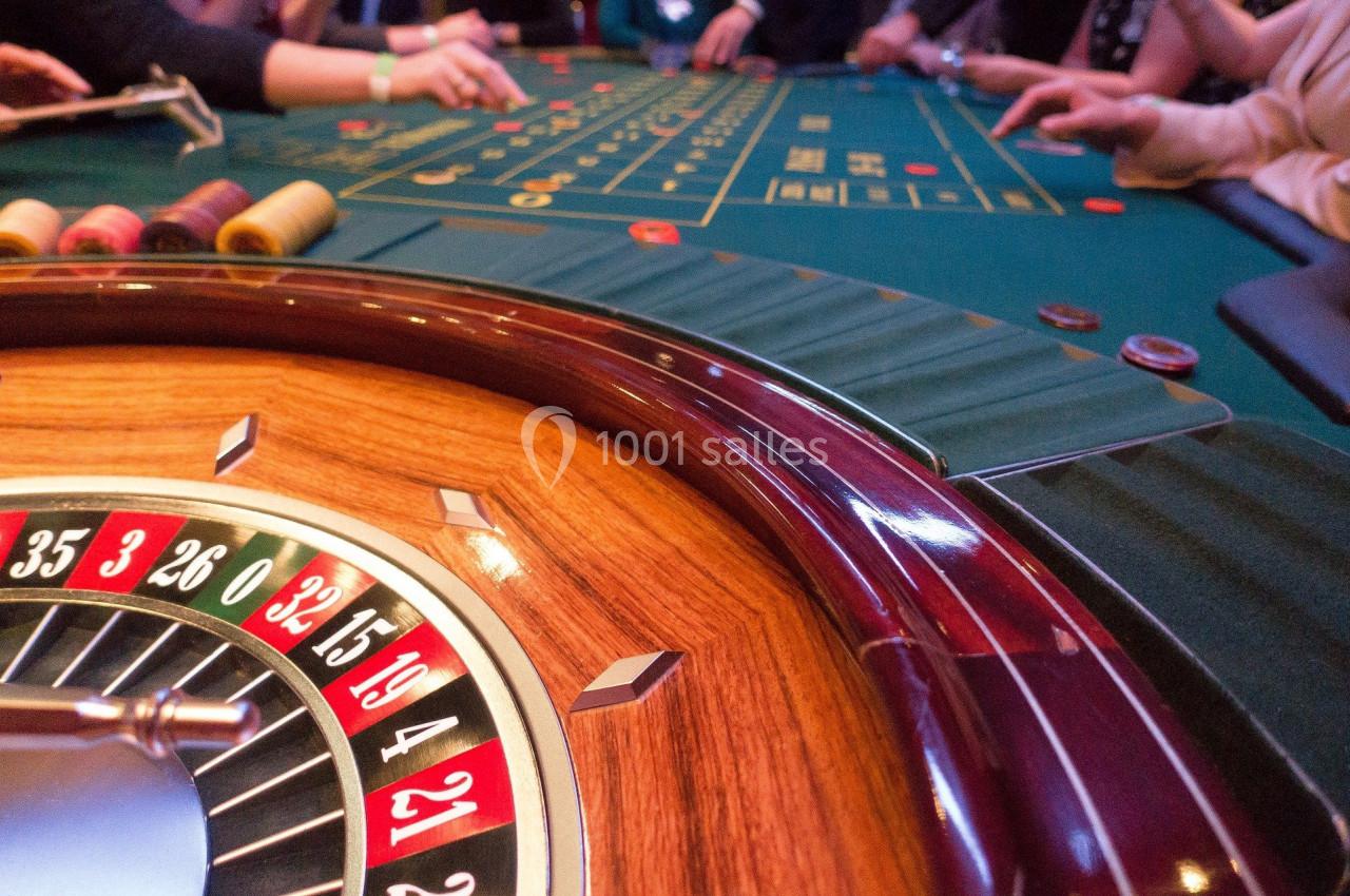 Roulette de casino en bois avec des jetons et des joueurs autour d'une table de jeu verte.