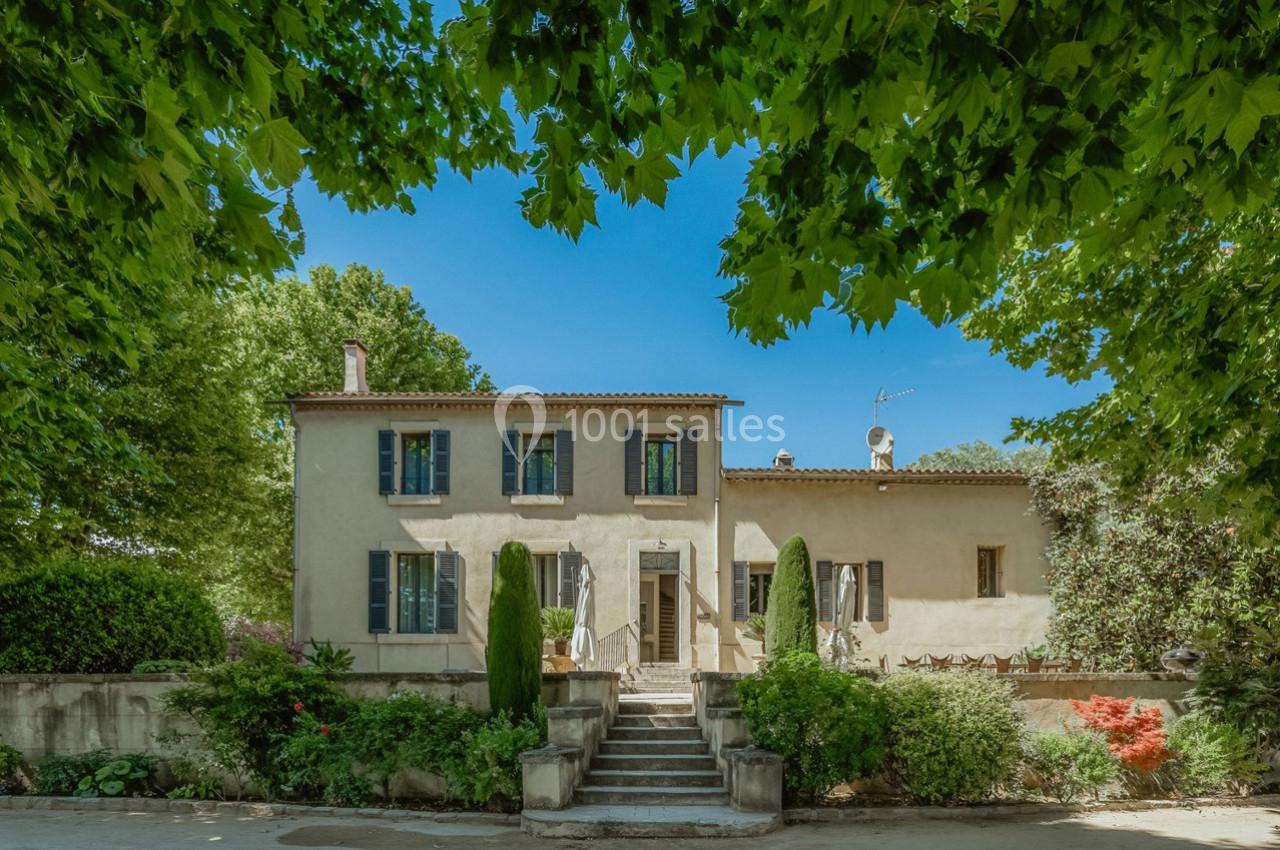 Façade d'une maison provençale entourée de verdure, avec des escaliers menant à l'entrée principale.