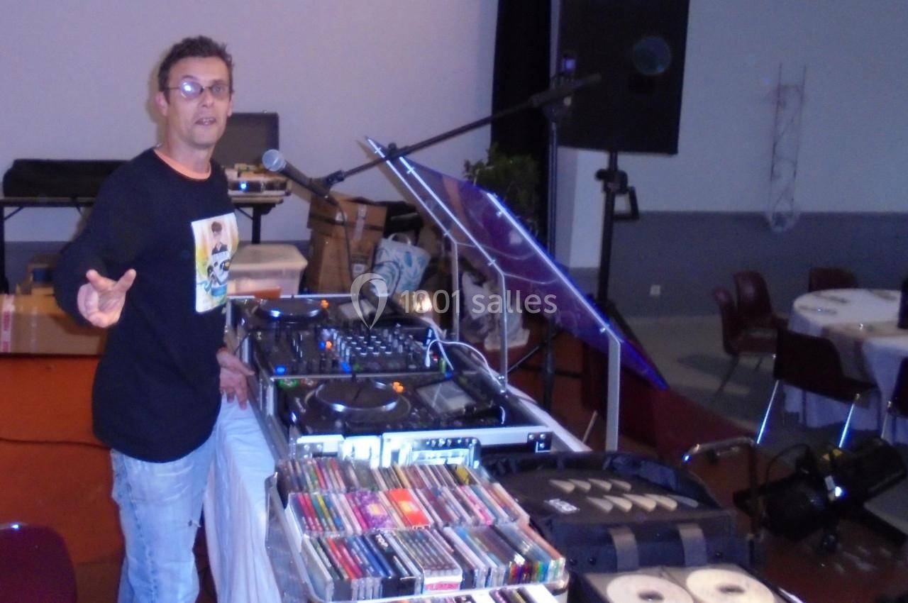 Un DJ devant une table de mixage avec des équipements audio et des cassettes dans une salle.