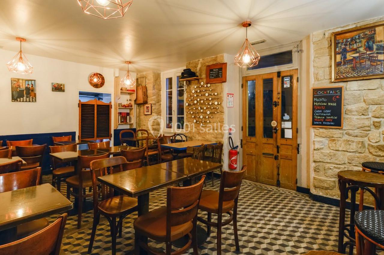 Salle de restaurant avec tables en bois, chaises assorties, murs en pierre et éclairage chaleureux.