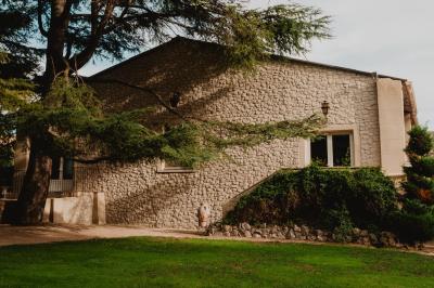Portail en fer forgé noir et mur en pierre avec inscription ’Les Charbenes du Donelay, Domaine de réception’.