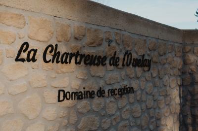 Portail en fer forgé noir et mur en pierre avec inscription ’Les Charbenes du Donelay, Domaine de réception’.