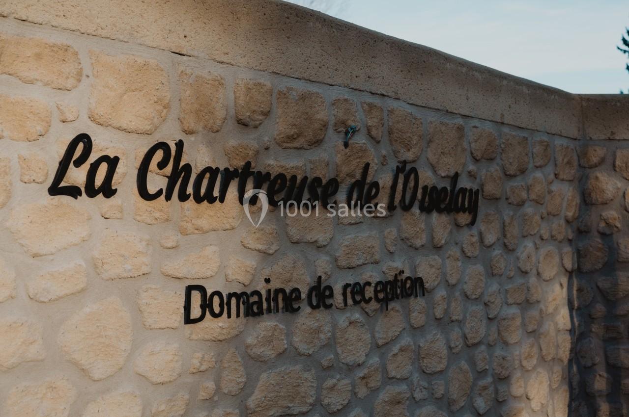 Mur en pierre avec l'inscription ’La Chartreuse de l'Oréalay, Domaine de réception’ en lettres noires.