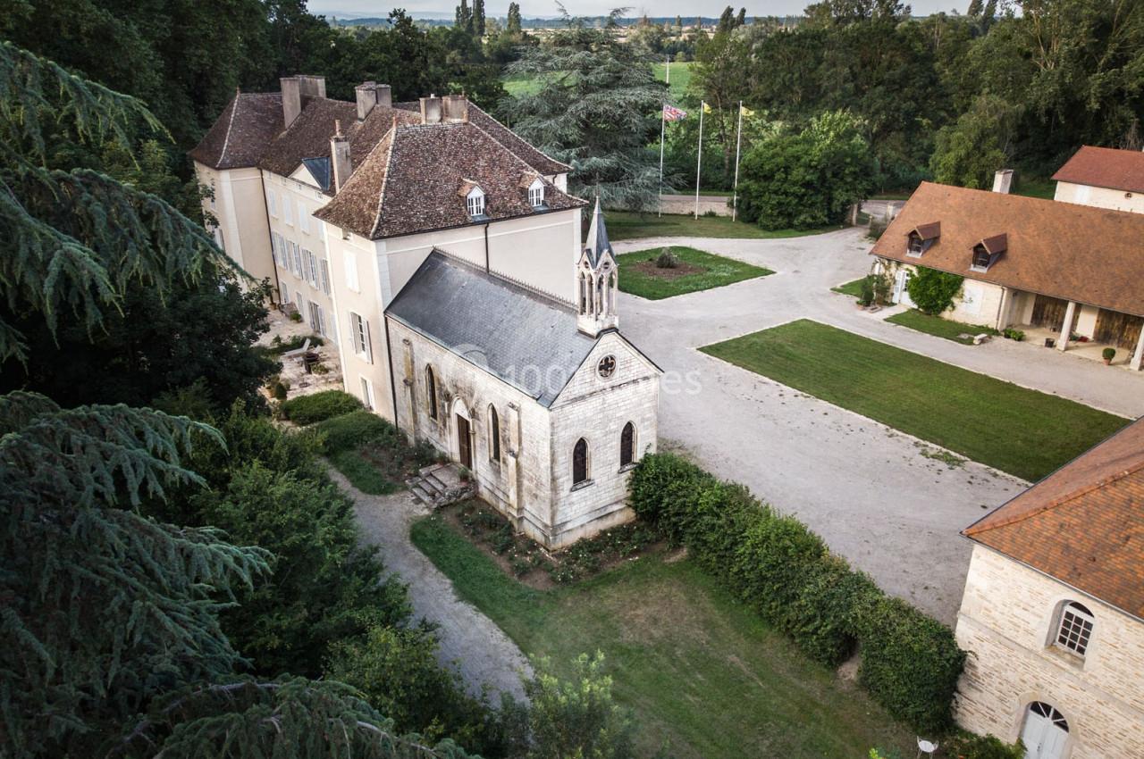 Vue aérienne d'un domaine avec une petite chapelle en pierre, des bâtiments anciens et un espace arboré.