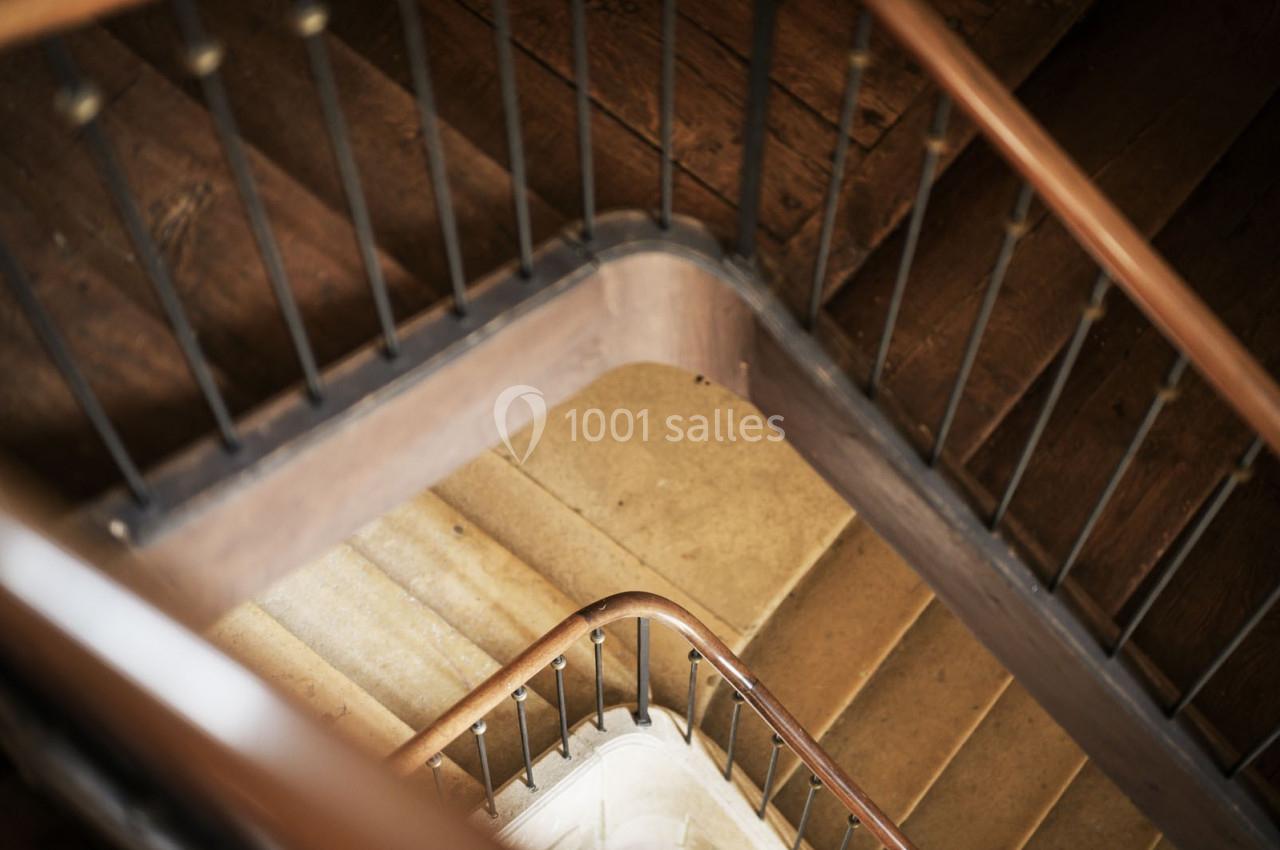 Escalier en colimaçon vu de dessus, avec des marches en pierre et une rampe en bois.