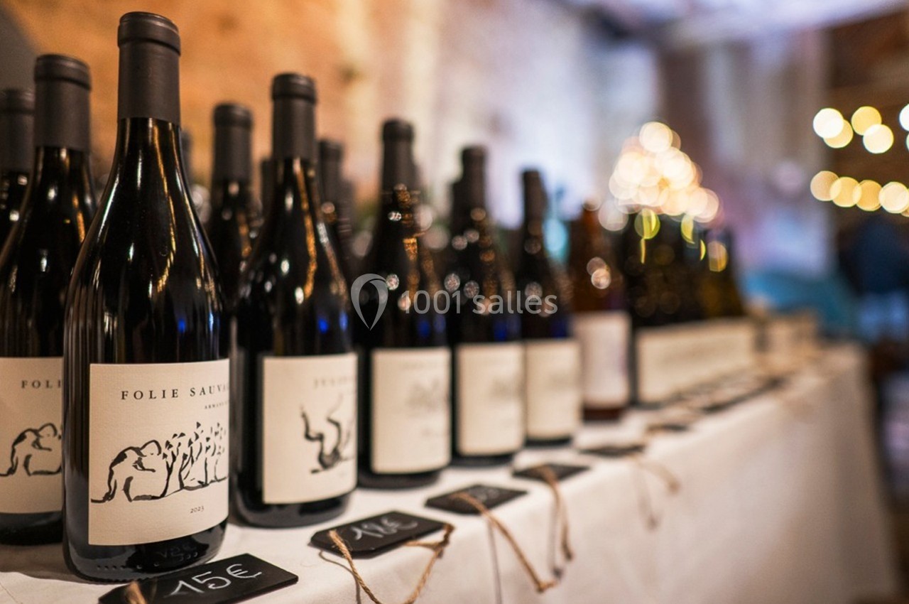 Bouteilles de vin alignées sur une table blanche avec étiquettes de prix visibles au premier plan.