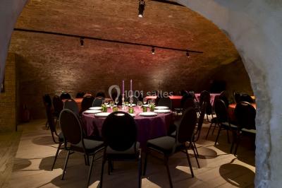 Cave voûtée en briques avec un comptoir éclairé et des bouteilles disposées dessus.