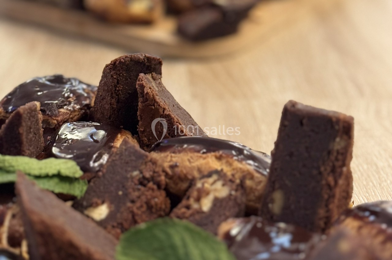 Assortiment de brownies au chocolat, certains nappés de glaçage, décorés de feuilles de menthe sur une table en bois.