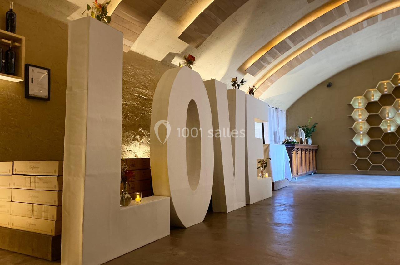 Grandes lettres blanches formant le mot ’LOVE’ dans une salle voûtée avec décoration chaleureuse et éclairage doux.