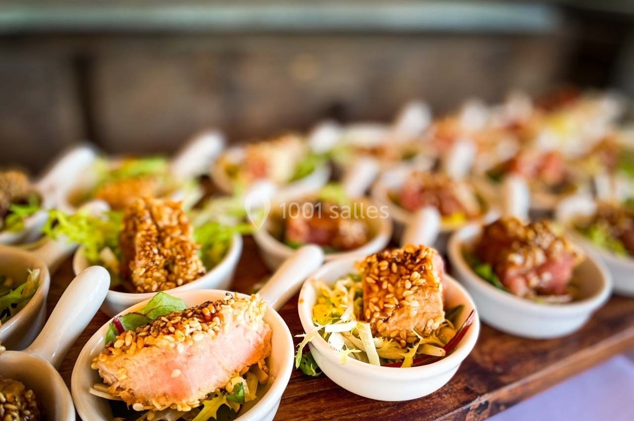 Petites portions de thon en croûte de sésame servies sur des cuillères avec une garniture de salade.