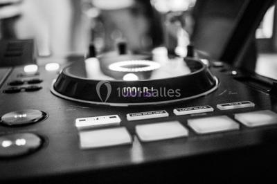 Structure en bois d'une halle éclairée par des lumières violettes, avec un toit en tuiles et des piliers en pierre.