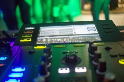 Structure en bois d'une halle éclairée par des lumières violettes, avec un toit en tuiles et des piliers en pierre.