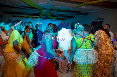 Structure en bois d'une halle éclairée par des lumières violettes, avec un toit en tuiles et des piliers en pierre.