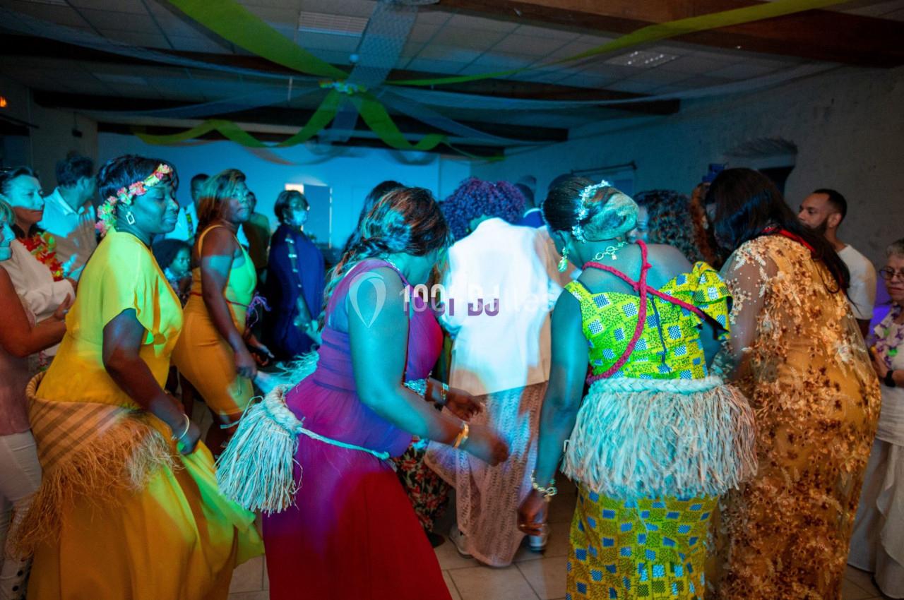 Des personnes dansent en groupe dans une salle décorée avec des rubans colorés, ambiance festive.