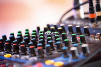Structure en bois d'une halle éclairée par des lumières violettes, avec un toit en tuiles et des piliers en pierre.