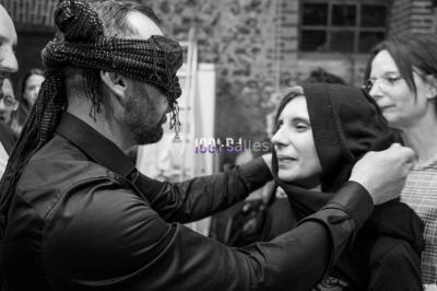 Structure en bois d'une halle éclairée par des lumières violettes, avec un toit en tuiles et des piliers en pierre.