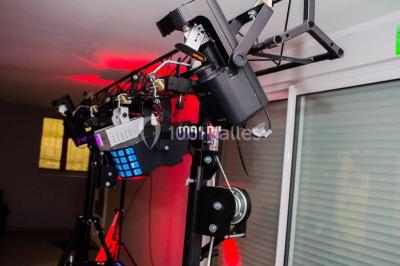 Structure en bois d'une halle éclairée par des lumières violettes, avec un toit en tuiles et des piliers en pierre.