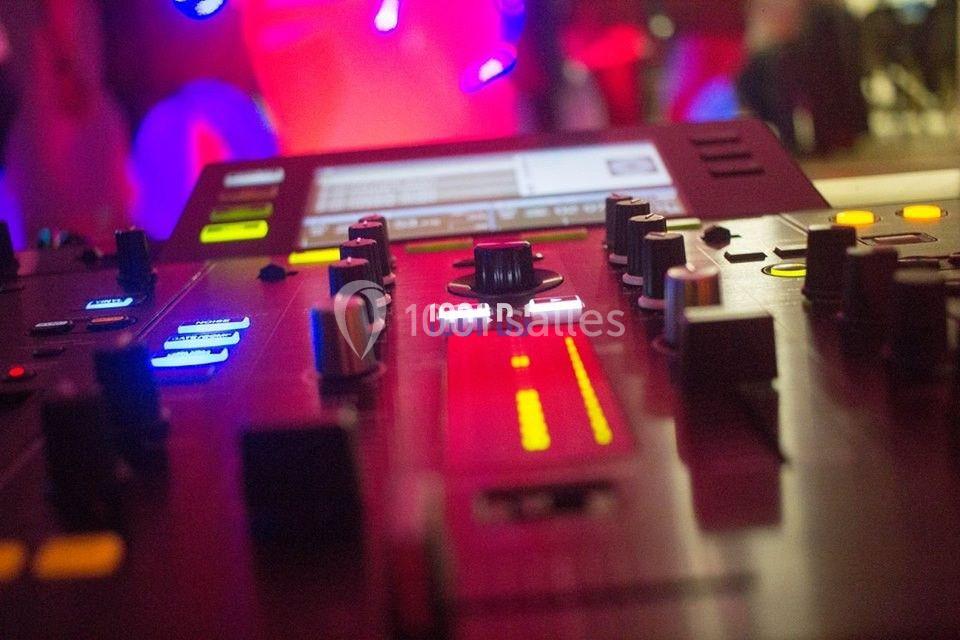 Table de mixage avec curseurs, boutons et lumières colorées, utilisée dans un environnement de musique ou d'événement.