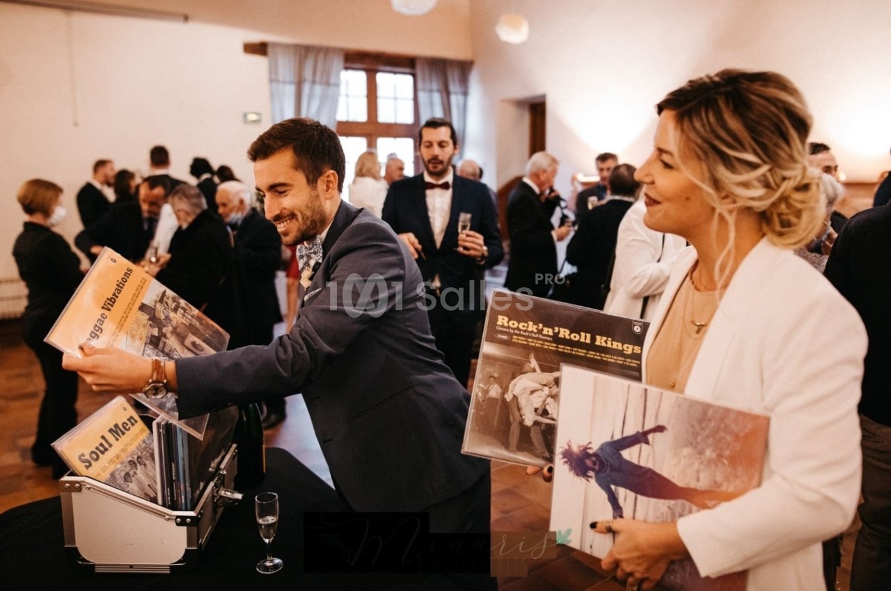 Un homme et une femme regardent des vinyles dans une salle remplie de personnes lors d'un événement.