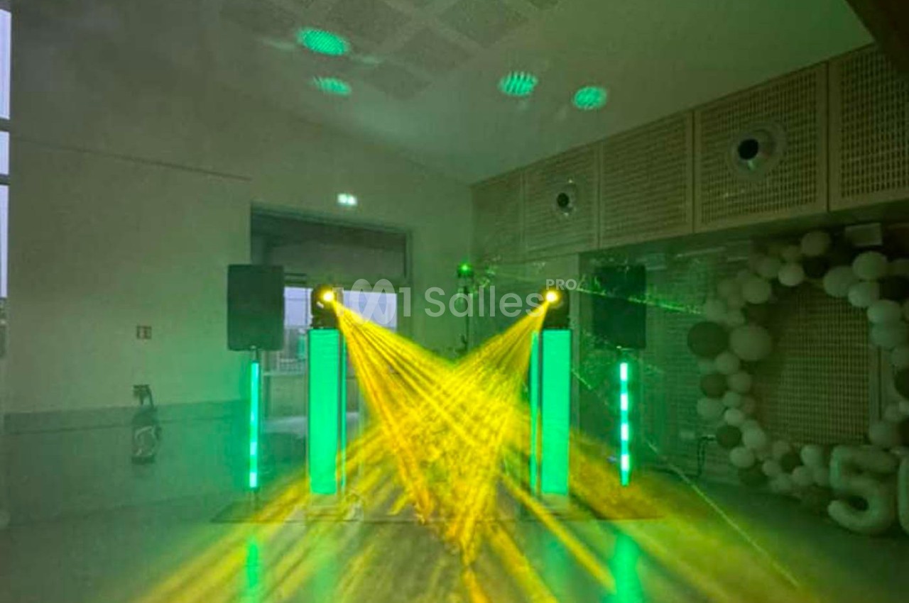 Jeux de lumières vertes et jaunes projetés dans une salle avec des enceintes et une décoration en ballons.