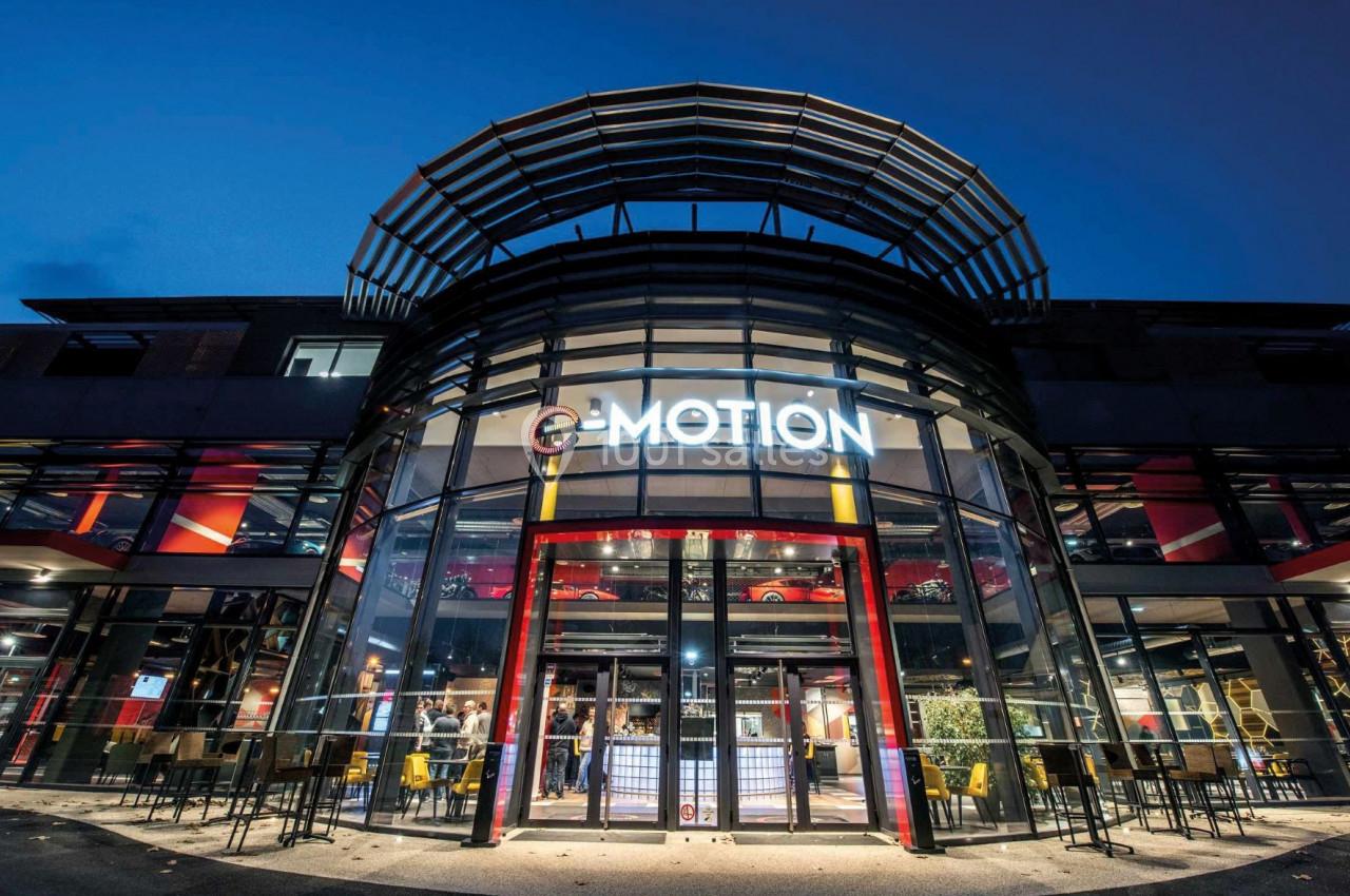 Façade vitrée d'un bâtiment moderne avec enseigne ’Motion’, éclairée en soirée, et des personnes à l'intérieur.