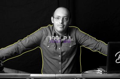 Main d'une personne ajustant un curseur sur une console de mixage DJ avec des boutons et lumières colorées.