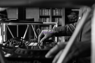 Main d'une personne ajustant un curseur sur une console de mixage DJ avec des boutons et lumières colorées.