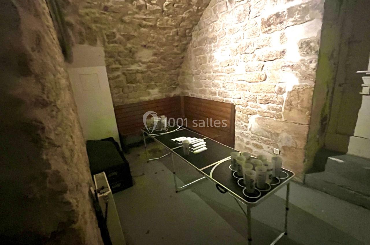 Table pliante avec tasses et serviettes dans une pièce voûtée aux murs en pierre éclairée par une lumière douce.