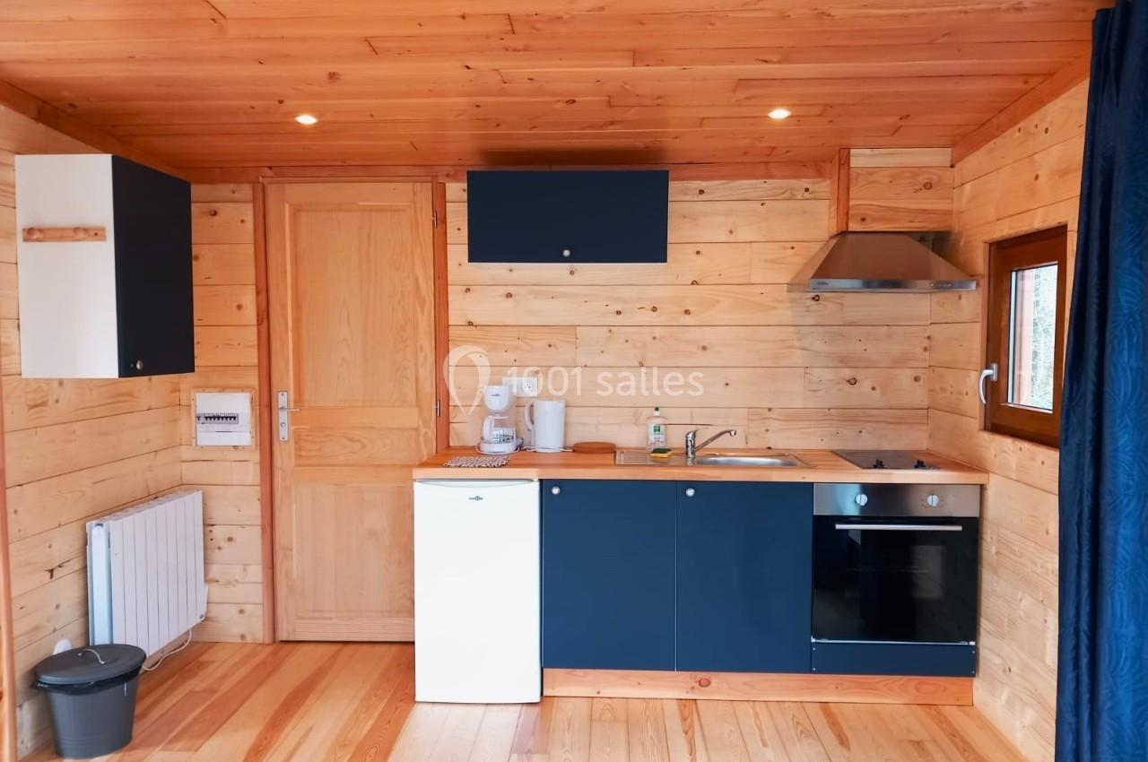 Cuisine en bois clair avec meubles bleu foncé, équipée d'un évier, d'une plaque de cuisson, d'un four et d'un réfrigérateur.
