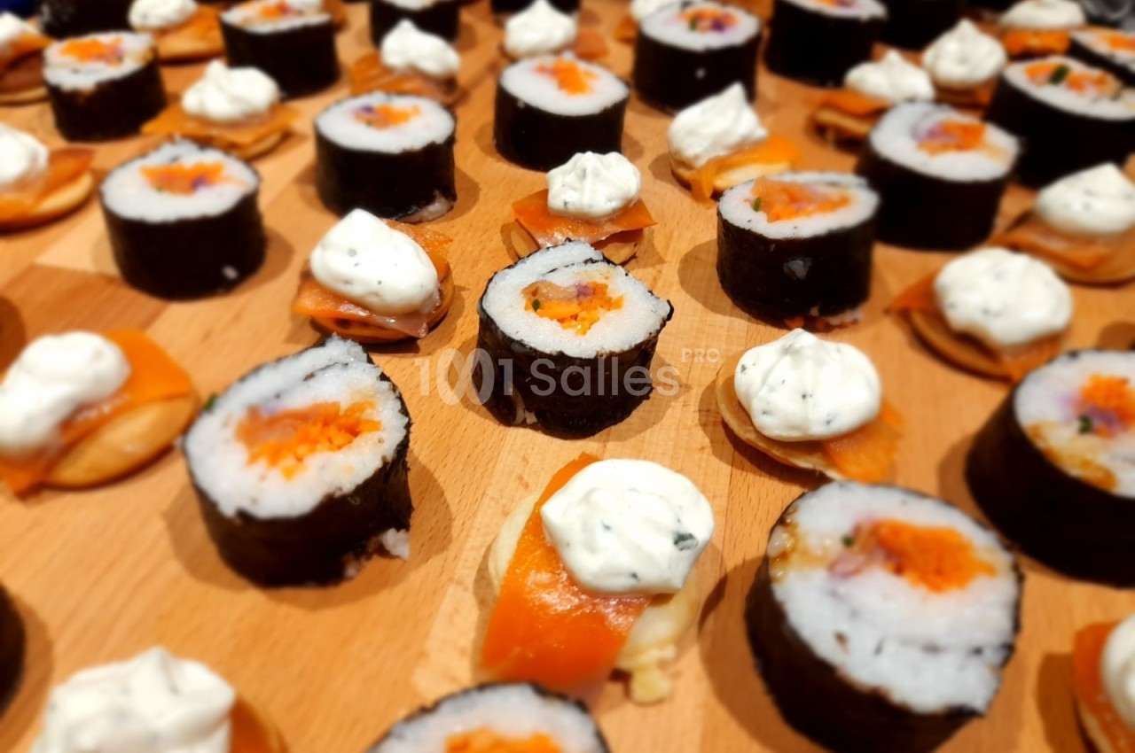Assortiment de sushis et makis disposés sur une table en bois, garnis de poisson, riz et crème.