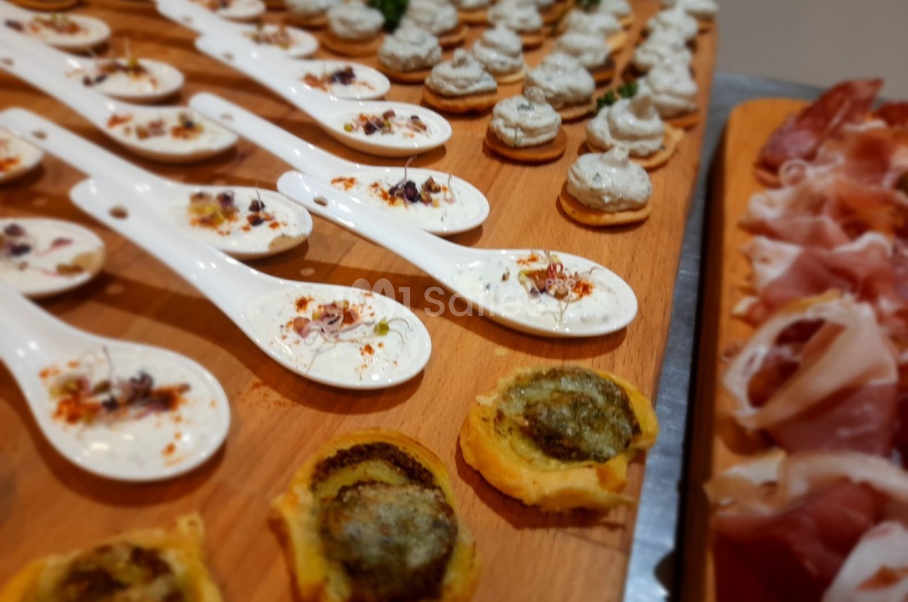 Plateau de bouchées apéritives variées, incluant cuillères garnies, toasts au pesto et tranches de charcuterie.