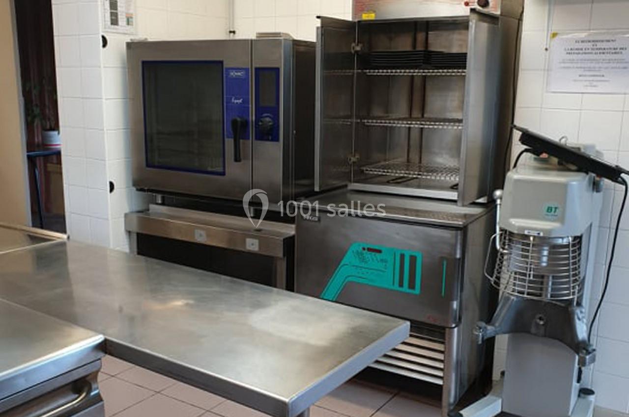 Cuisine professionnelle avec four, cellule de refroidissement, batteur mélangeur et plan de travail en inox.