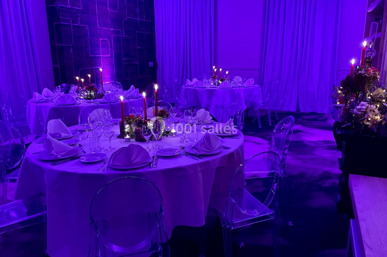 Location salle Lille (Nord) - Les Salons de l'Urban #4 Salle de réception éclairée en violet avec tables rondes dressées, nappes blanches, bougies et décorations florales.