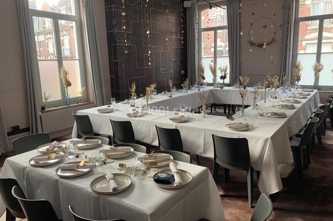 Location salle Lille (Nord) - Les Salons de l'Urban #9 Salle de réception lumineuse avec tables dressées en U, nappes blanches, vaisselle élégante et décorations florales.