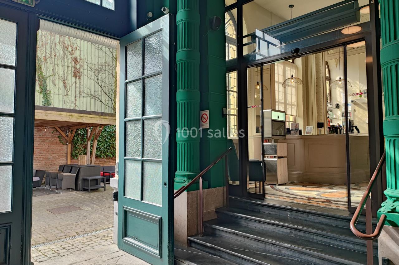 Location salle Lille (Nord) - Les Salons de l'Urban #31 Entrée d'un bâtiment avec des portes ouvertes, escalier menant à un intérieur lumineux et terrasse extérieure aménagée.