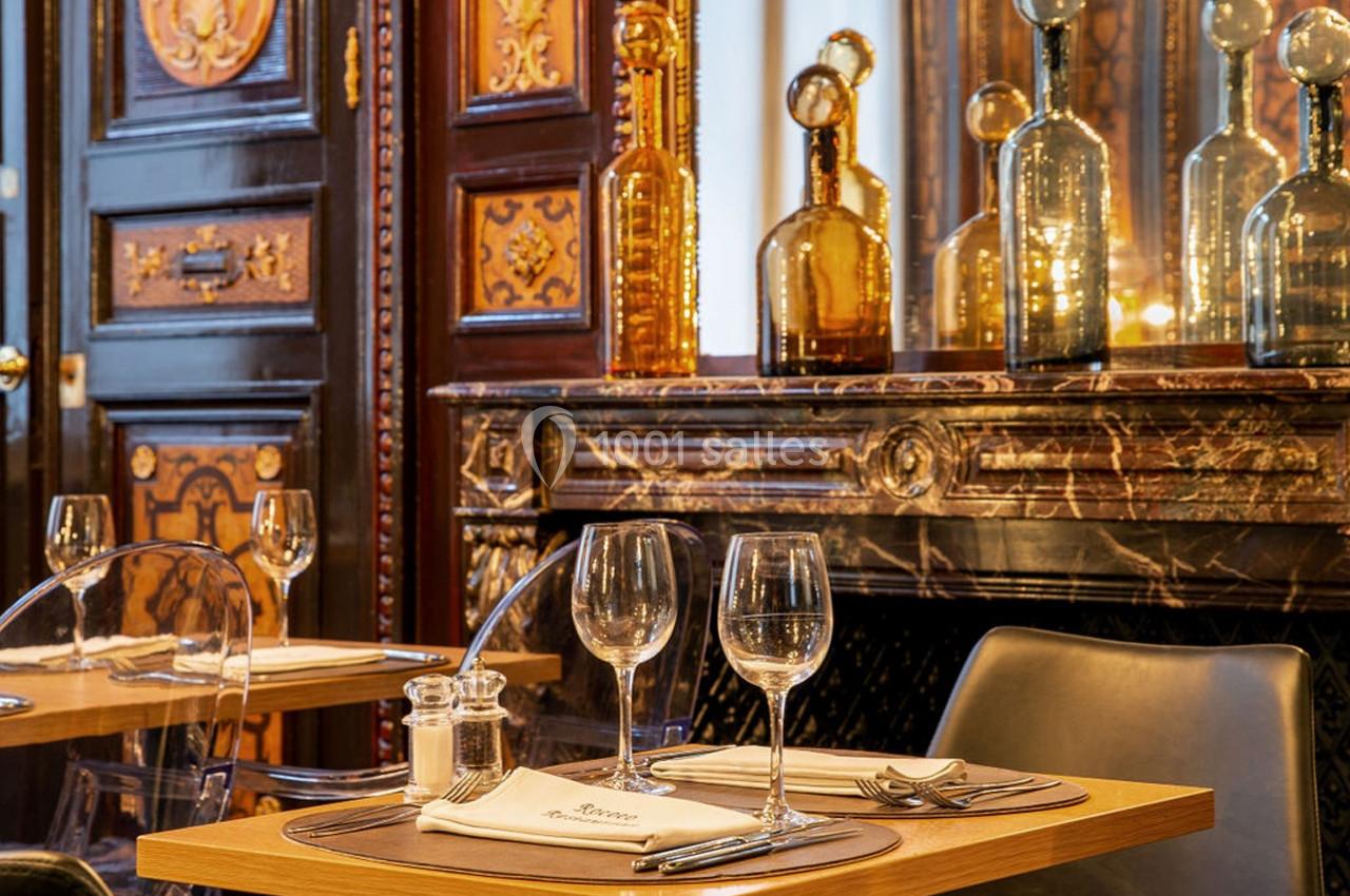 Location salle Lille (Nord) - Les Salons de l'Urban #24 Tables dressées avec verres et couverts dans un restaurant élégant, décoré de boiseries et de bouteilles en verre.