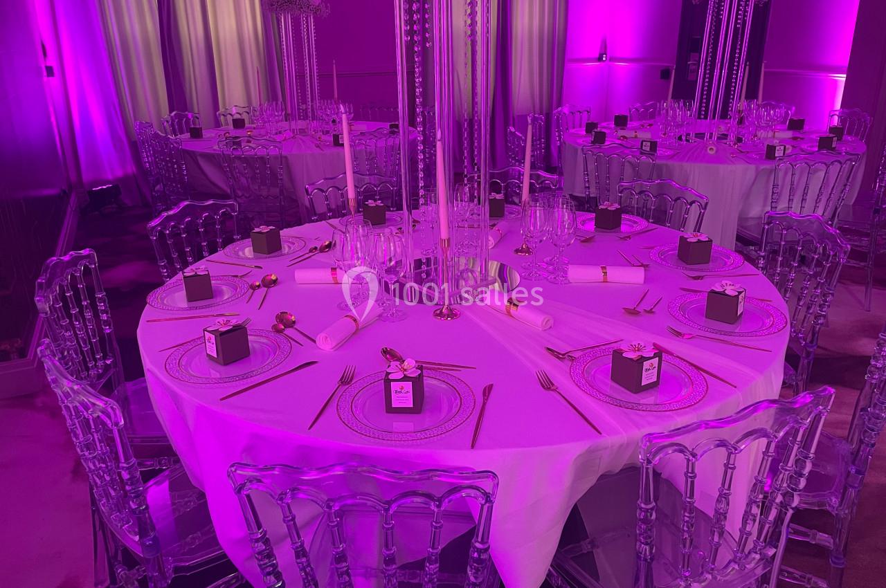 Location salle Lille (Nord) - Les Salons de l'Urban #3 Table ronde décorée pour un événement, avec nappes blanches, couverts dorés, bougies et éclairage violet.