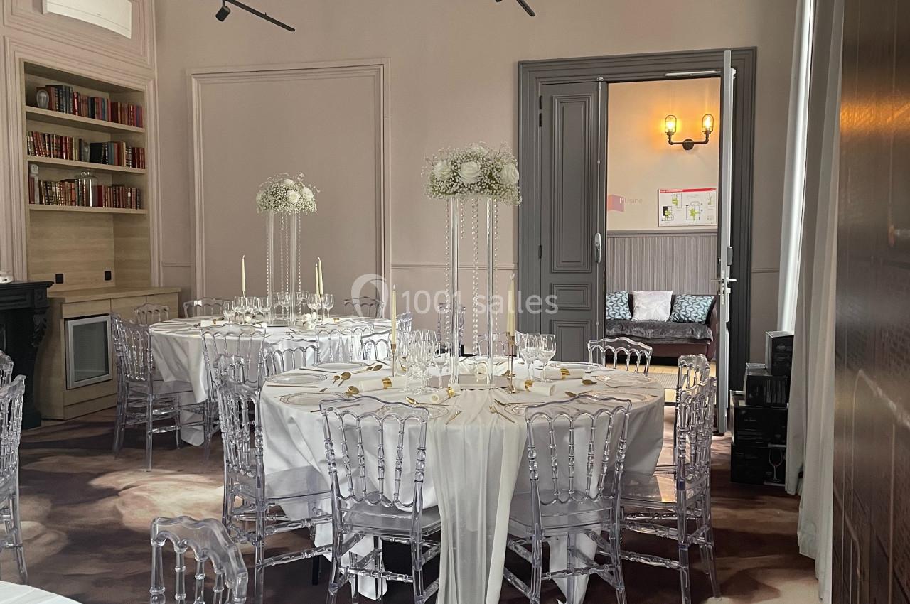 Location salle Lille (Nord) - Les Salons de l'Urban #2 Salle élégante décorée pour un événement, avec tables rondes, nappes blanches, chaises transparentes et centres de table…