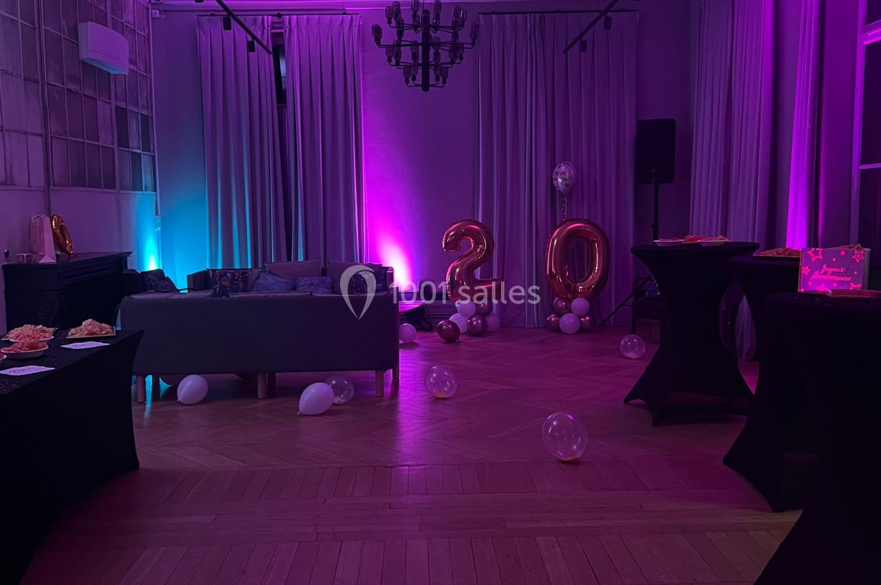 Location salle Lille (Nord) - Les Salons de l'Urban #21 Salle décorée pour une fête avec éclairage violet, ballons ’20’, tables hautes et canapé en arrière-plan.