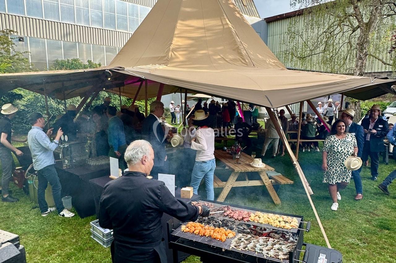 Location salle Lille (Nord) - Les Salons de l'Urban #13 Un cuisinier prépare des brochettes sur un barbecue lors d'un événement en plein air sous une tente tipi.