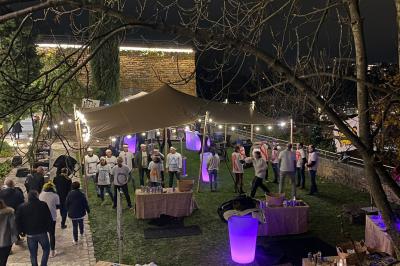 Vue nocturne d'un événement en plein air avec des stands sous une tente éclairée et des participants rassemblés.