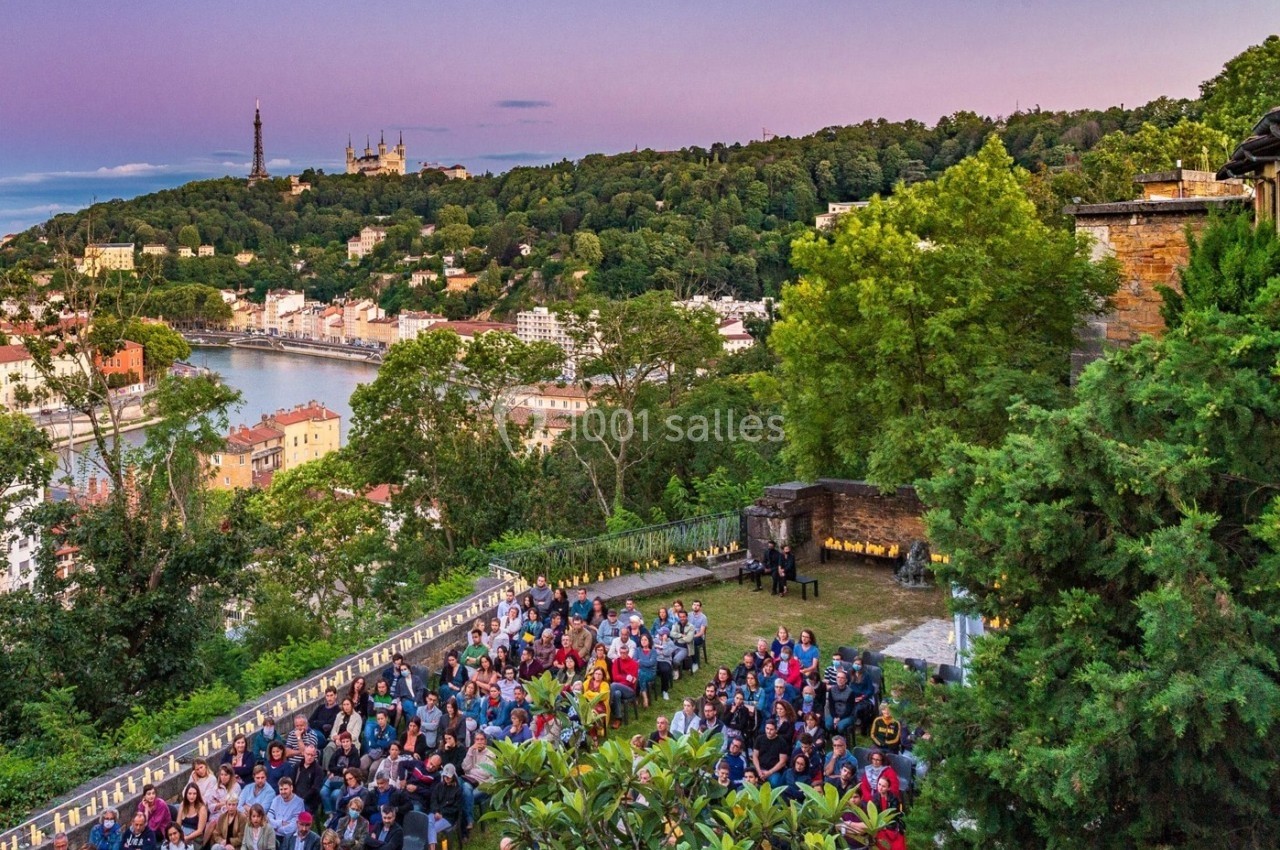 Location salle Lyon 9 (Rhône) - Le Fort de Vaise #1 Vue d'un événement en plein air avec des participants, surplombant une ville, une rivière et des collines verdoyantes au…