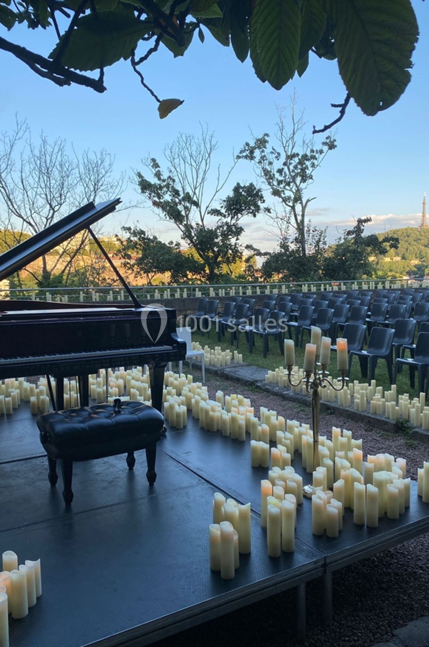 Location salle Lyon 9 (Rhône) - Le Fort de Vaise #9 Scène extérieure avec un piano à queue entouré de bougies, des rangées de chaises vides en arrière-plan.