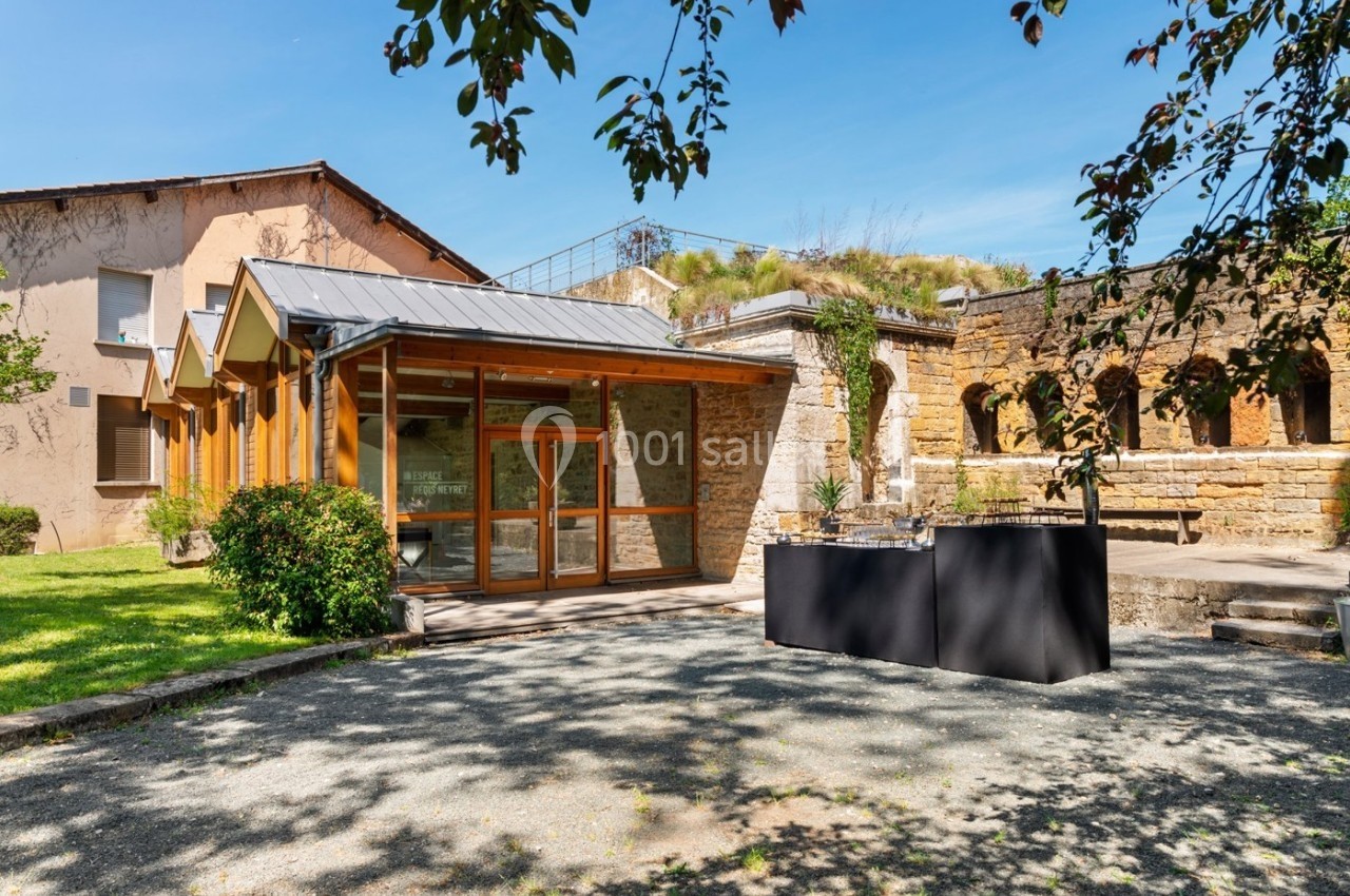 Location salle Lyon 9 (Rhône) - Le Fort de Vaise #16 Entrée d'un bâtiment moderne avec façade en bois, entouré de verdure et de ruines en pierre sous un ciel dégagé.