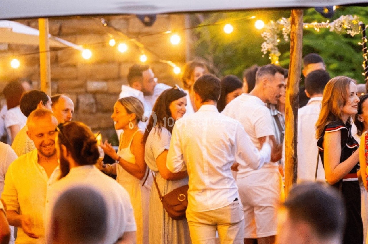Location salle Lyon 9 (Rhône) - Le Fort de Vaise #20 Groupe de personnes discutant et partageant un moment convivial lors d'un événement en extérieur, éclairé par des guirlandes…