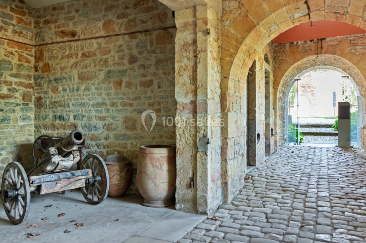 Location salle Lyon 9 (Rhône) - Le Fort de Vaise #21 Un vieux canon sur roues et des jarres en terre cuite sont disposés sous une arcade en pierre dans une cour pavée.