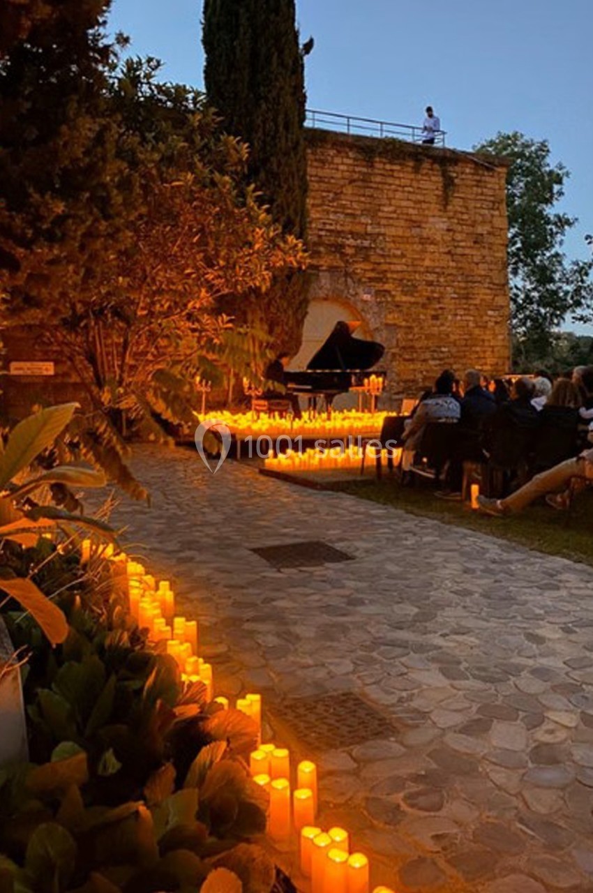 Location salle Lyon 9 (Rhône) - Le Fort de Vaise #35 Allée pavée bordée de bougies menant à un piano en plein air, entouré de spectateurs au crépuscule.
