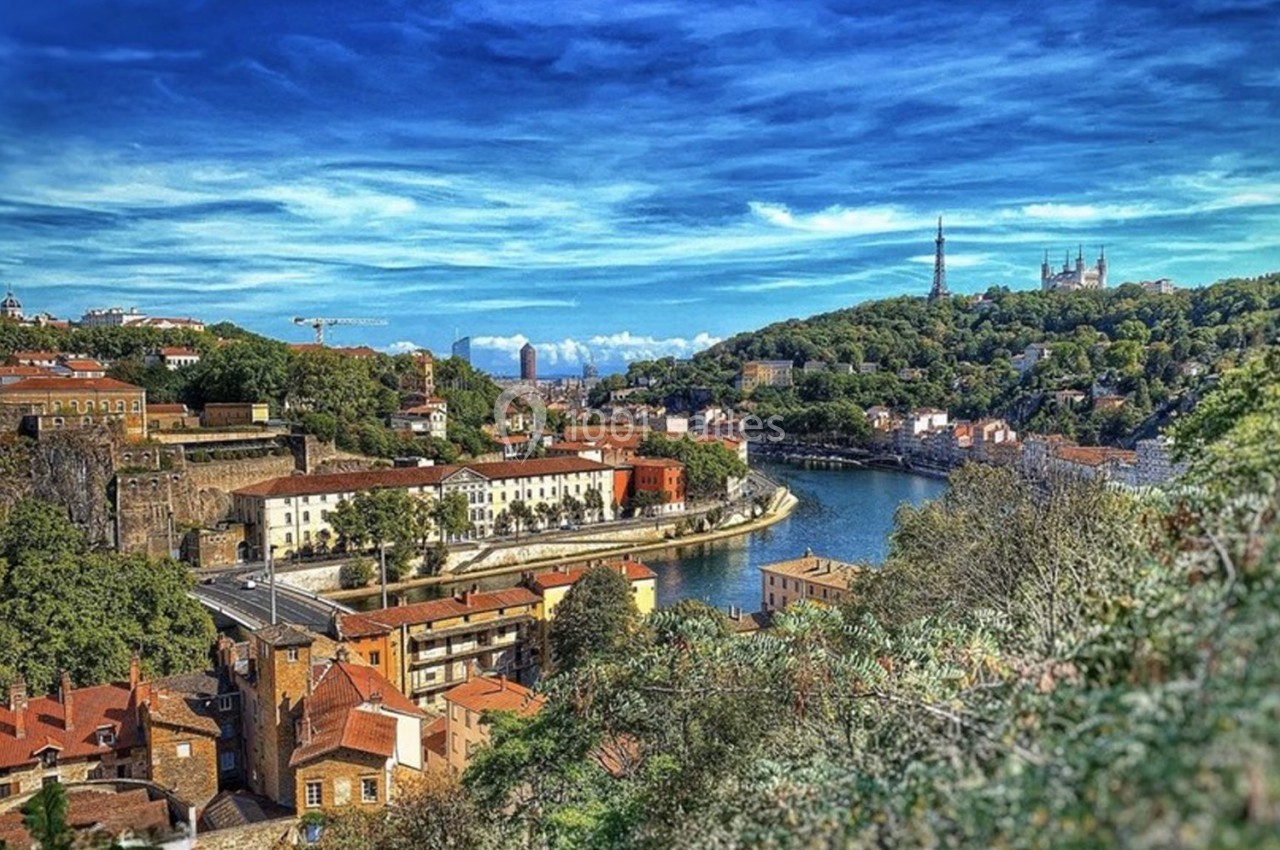 Location salle Lyon 9 (Rhône) - Le Fort de Vaise #36 Vue panoramique d'une ville avec des bâtiments en briques, une rivière sinueuse et des collines verdoyantes sous un ciel…